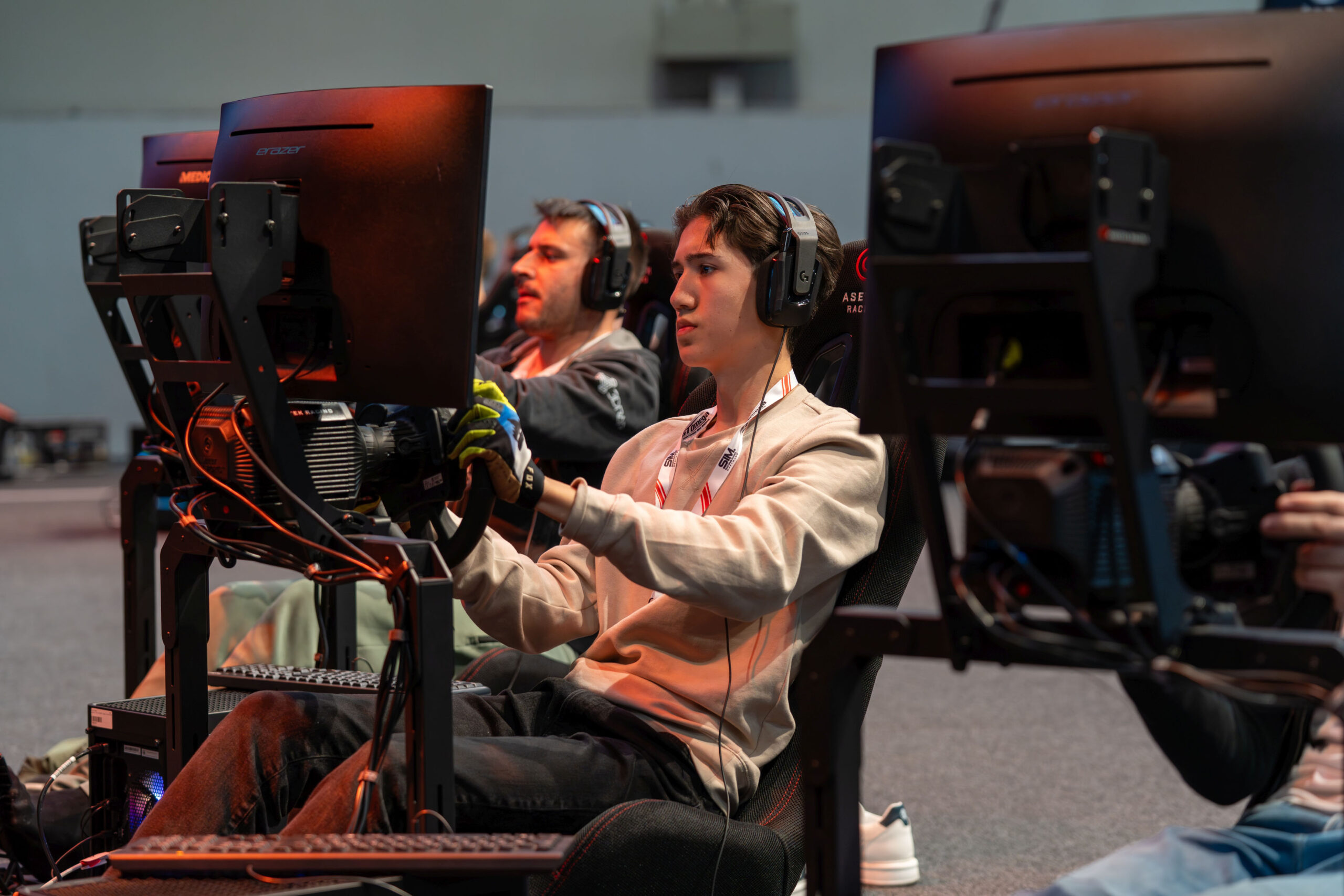 Two people in racing sim rigs.