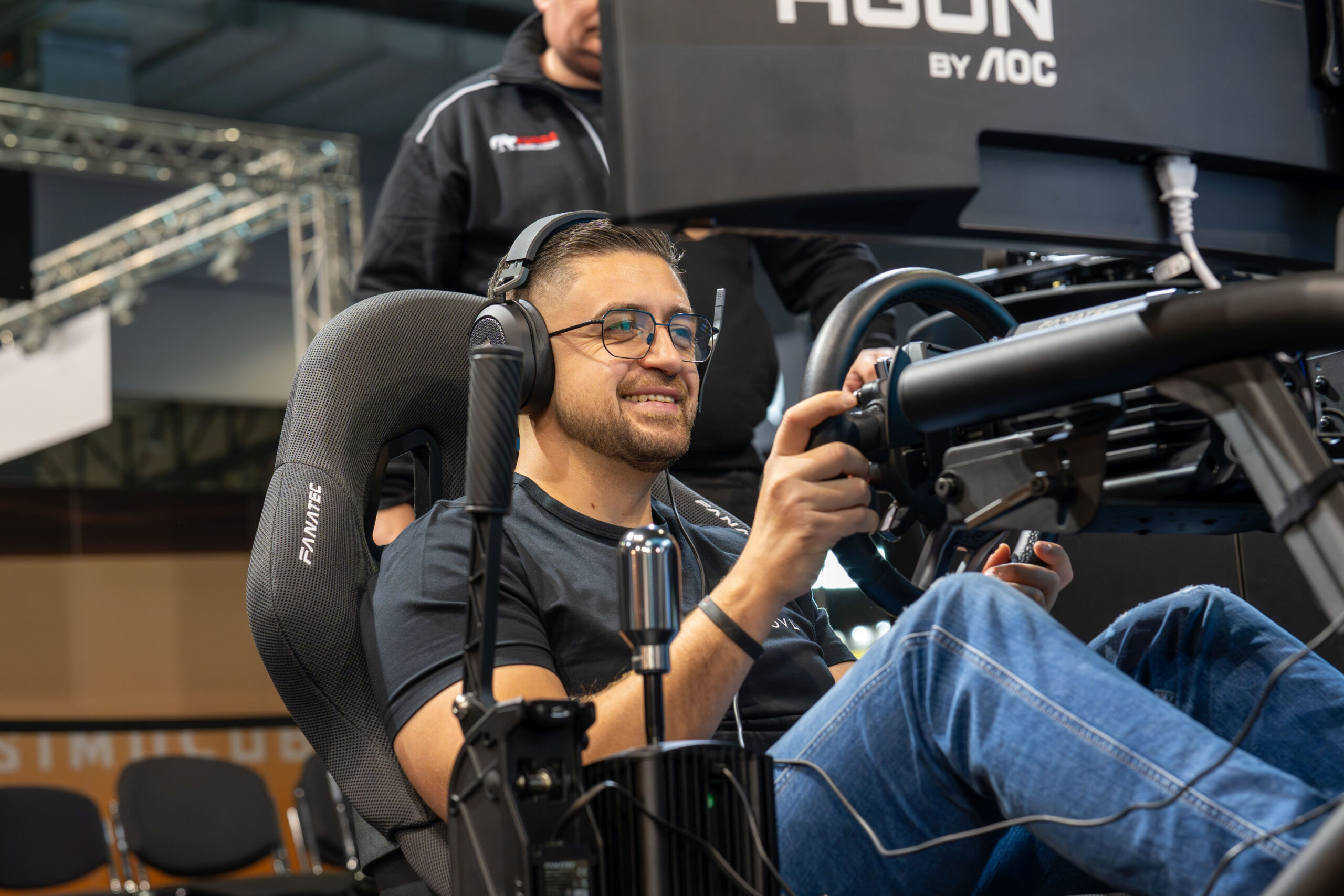 A convention attendee sitting in a racing sim rig